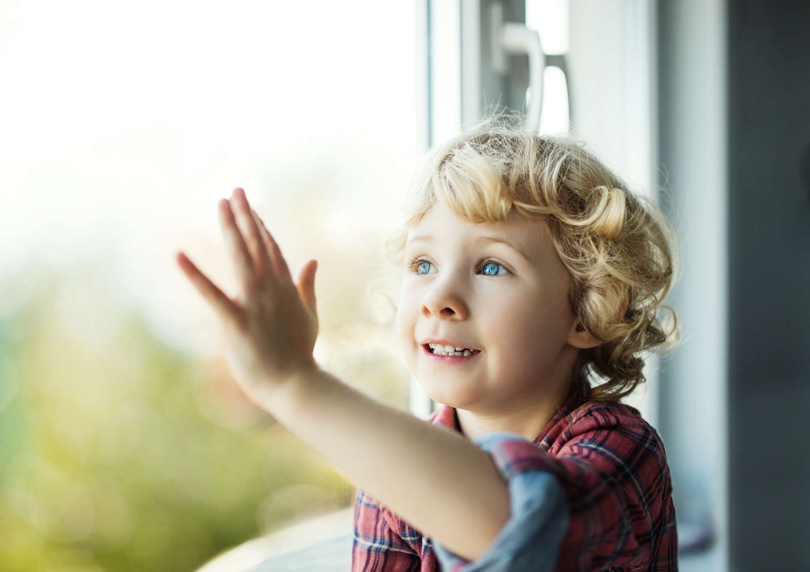Adorable blond toddler girl looking out of the window