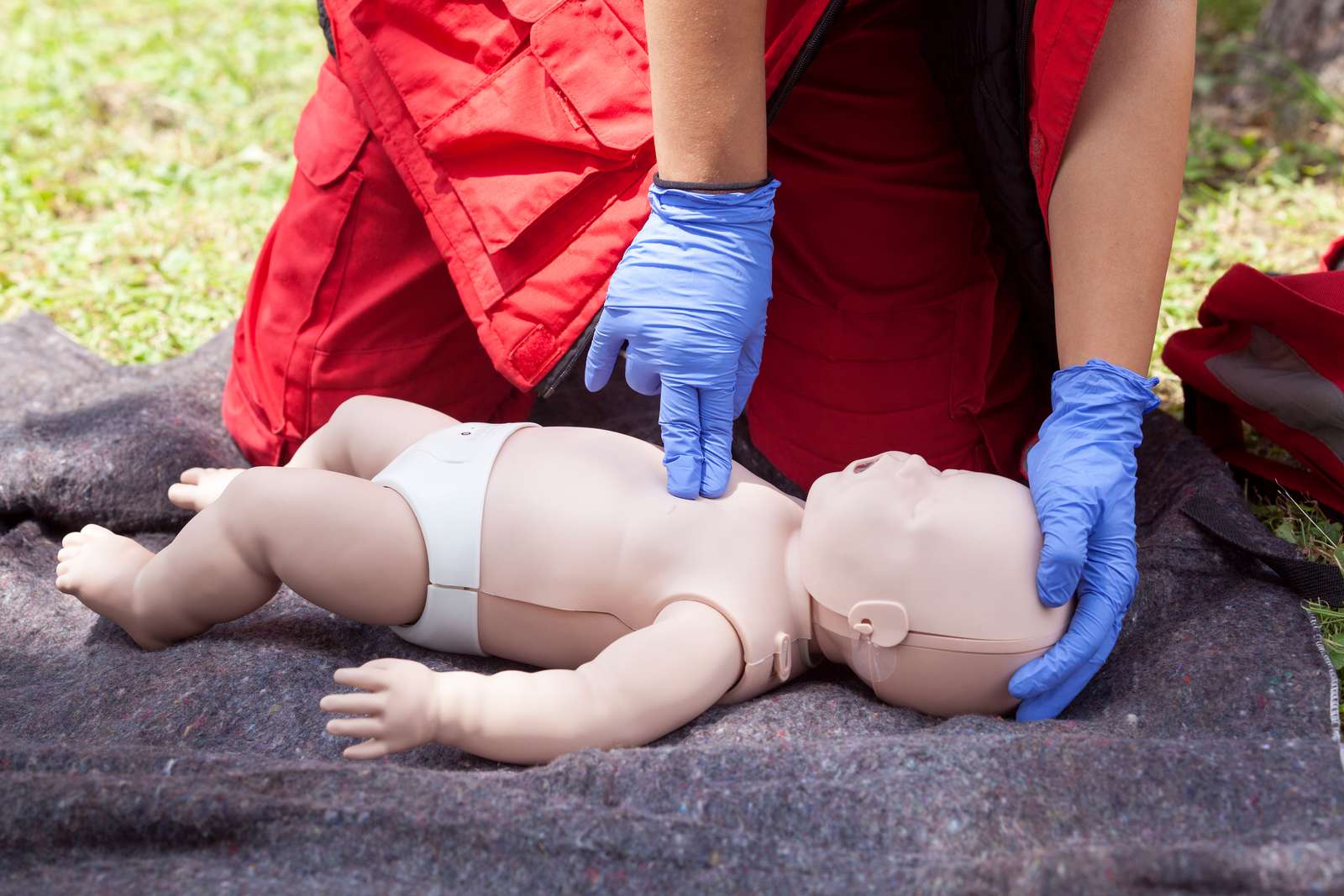 Paramedic performing CPR on baby dummy with two-finger chest compression