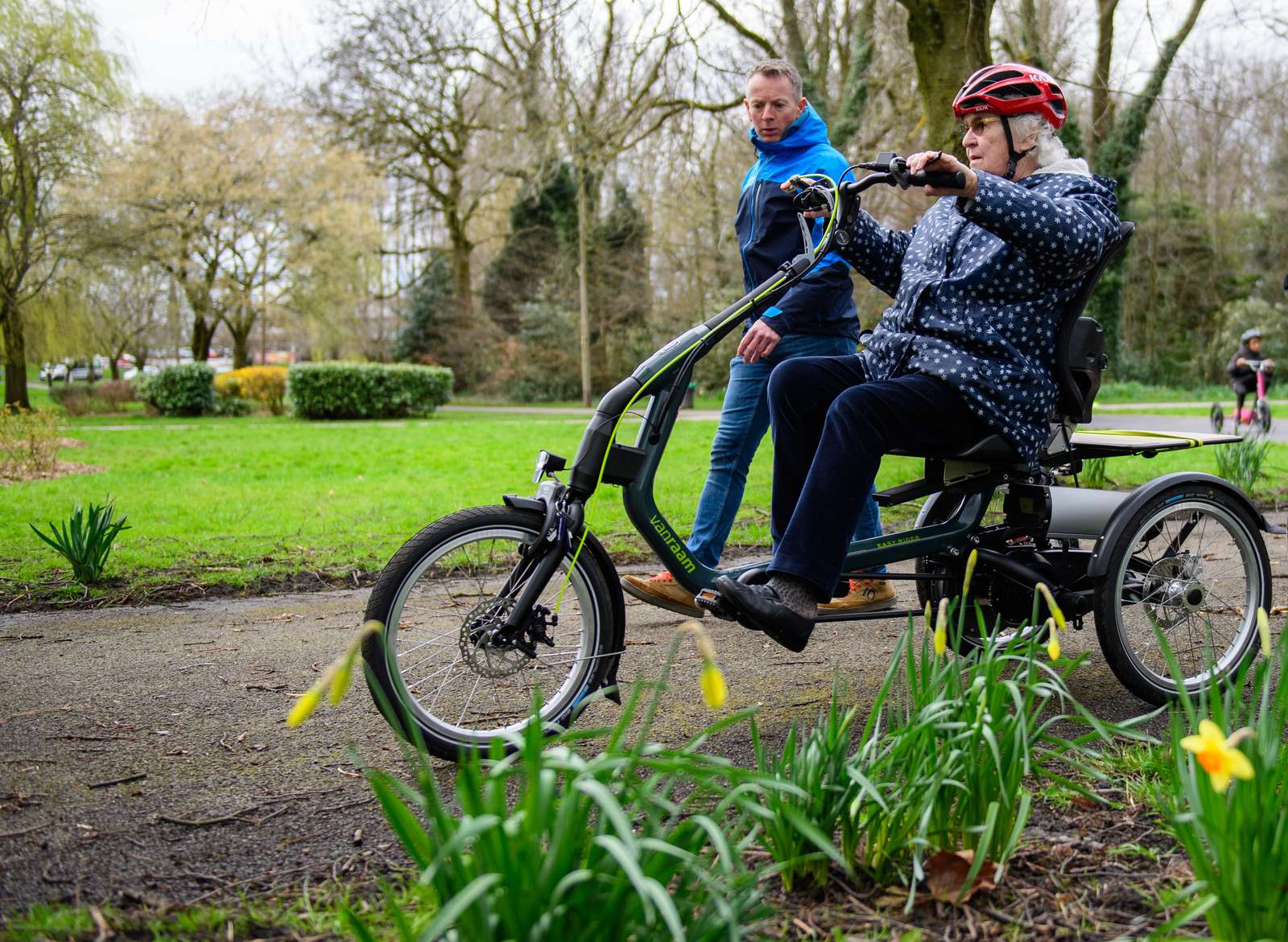 Cycling UK's Ross Adams walks beside a participant as she rides an e-trike through Debdale Park, Manchester on March 21 2023. Public event took place to mark the launch of Cycling UK's new e-cycle scheme, Making cycling e-asier, at Wheels for All.