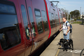 Blind man with dog at train station