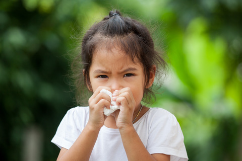 Sick little asian girl wiping or cleaning nose with tissue on her hand