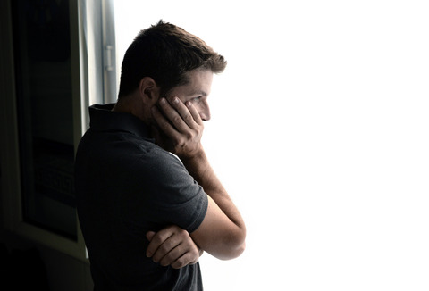 attractive man looking through window suffering emotional crisis and depression