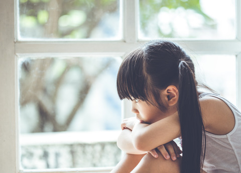 Depressed Little girl  near window at home, closeup