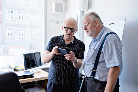 Two elderly men using smartphone
