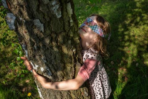 Pige holder om træ med tørklæde for øjnene til spilopspejd
