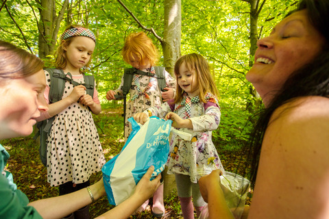 Piger kigger i plastikpose i skoven til spilopspejd