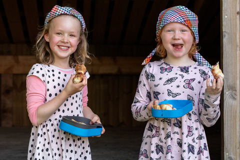 To piger spiser snobrød af tallerkener og griner til spilopspejd 