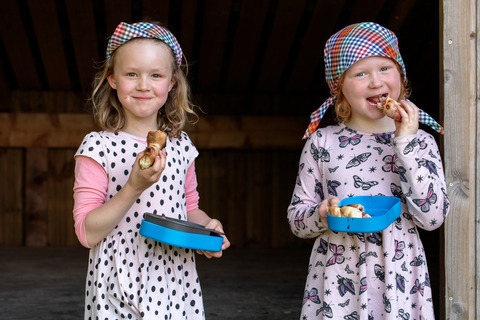 To piger spiser snobrød af tallerkener til spilopspejd