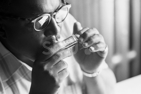 Sonny Terry. Playing the harmonica at his home in Harlem, New York, 1960