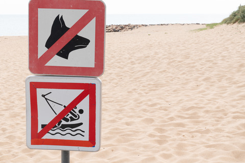 Prohibiting signs no dog no boat sign on sand beach sea coast