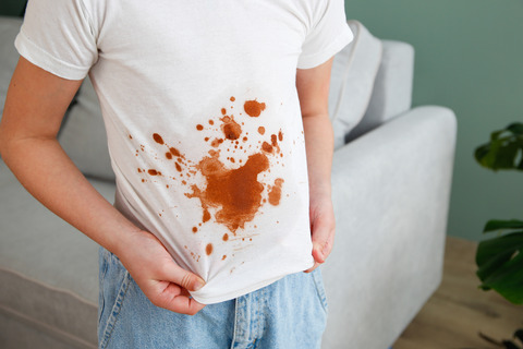 The child spilled coffee on his clothes. The concept of a stain on a t-shirt.